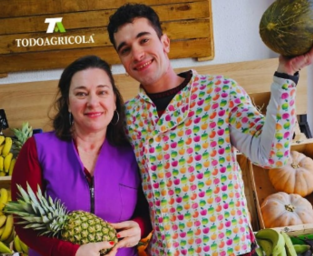 El equipo de Todo Agrícola en la tienda, bajo el rótulo, con una piña y un melón